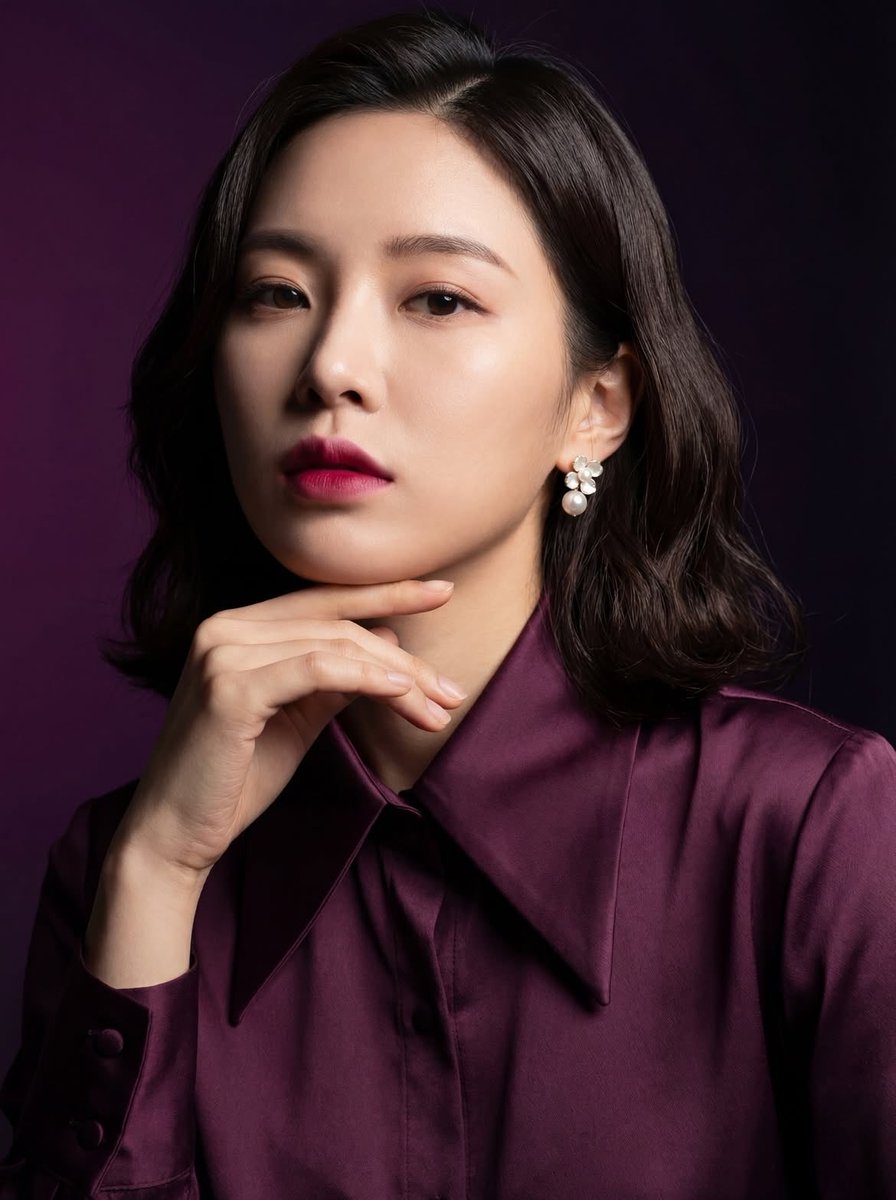"一张优雅东亚女性的影棚肖像,肩长的深色头发,身着深梅紫色缎面衬衫,柔和自然的妆容搭配大胆的粉色唇彩,佩戴珍珠花卉耳环,手轻托下巴,神情自信而…, 图片 1