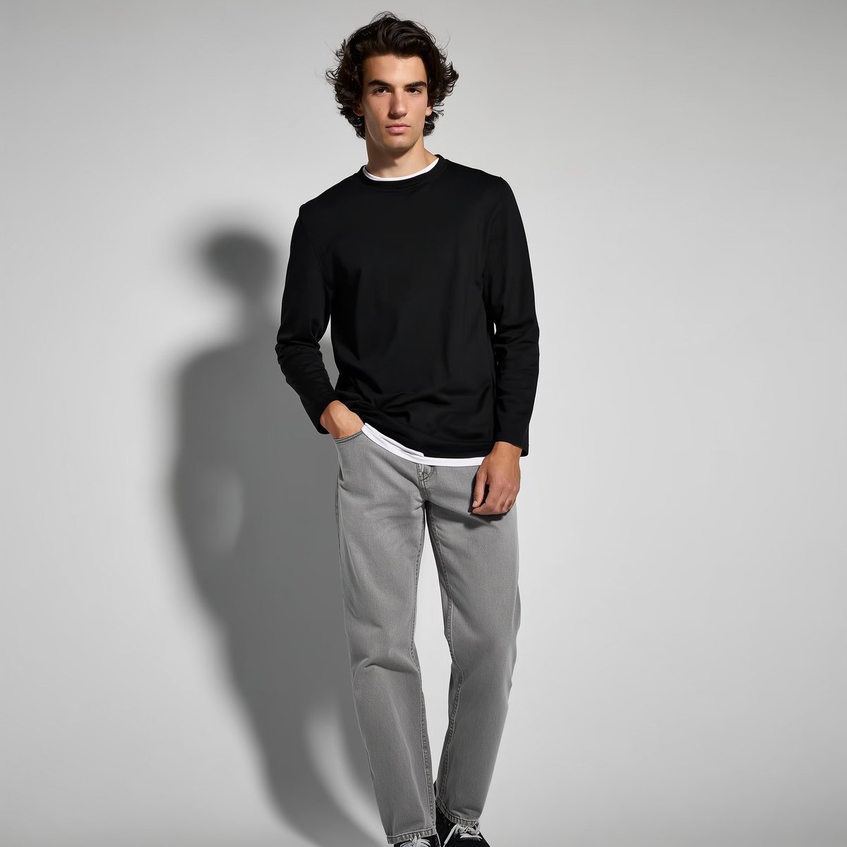 A full-body fashion portrait of a young male model standing against a smooth ne…