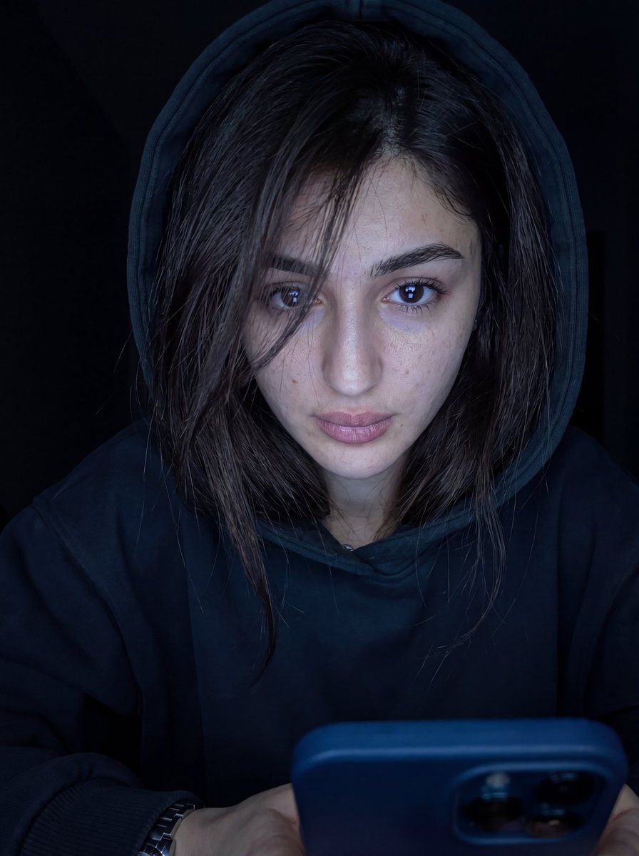 超写实特写肖像，画中人物为男性或女性（来自上传图像），凌乱的头发部分遮住一只眼睛，身穿深色 oversized 帽衫，帽子微微拉起。脸部由下方…, 图片 1