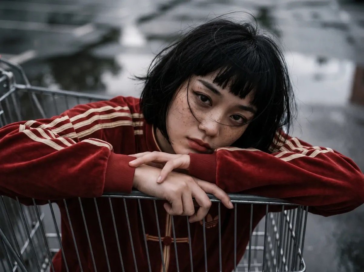 女性角色位于购物推车内部,以推车内部为视角向上望向她的脸部,戏剧性的透视畸变,一条腿靠近镜头,姿势"无所谓"且放松:,超大红色(偏红)的阿迪达…, 图片 2