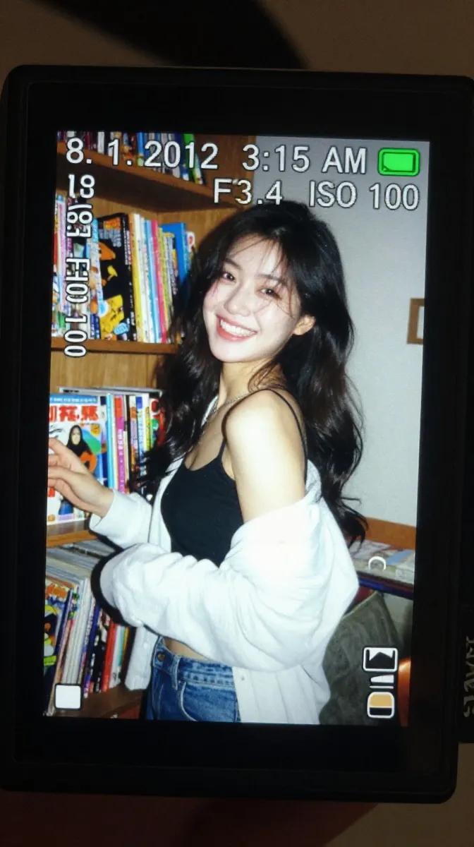 一个真实感的特写镜头,拍摄的是在昏暗室内环境中明亮发光的一台小型数码相机屏幕。LCD 屏幕上显示着一张抓拍风格的早期 2010 年代风格照片,…, 图片 1