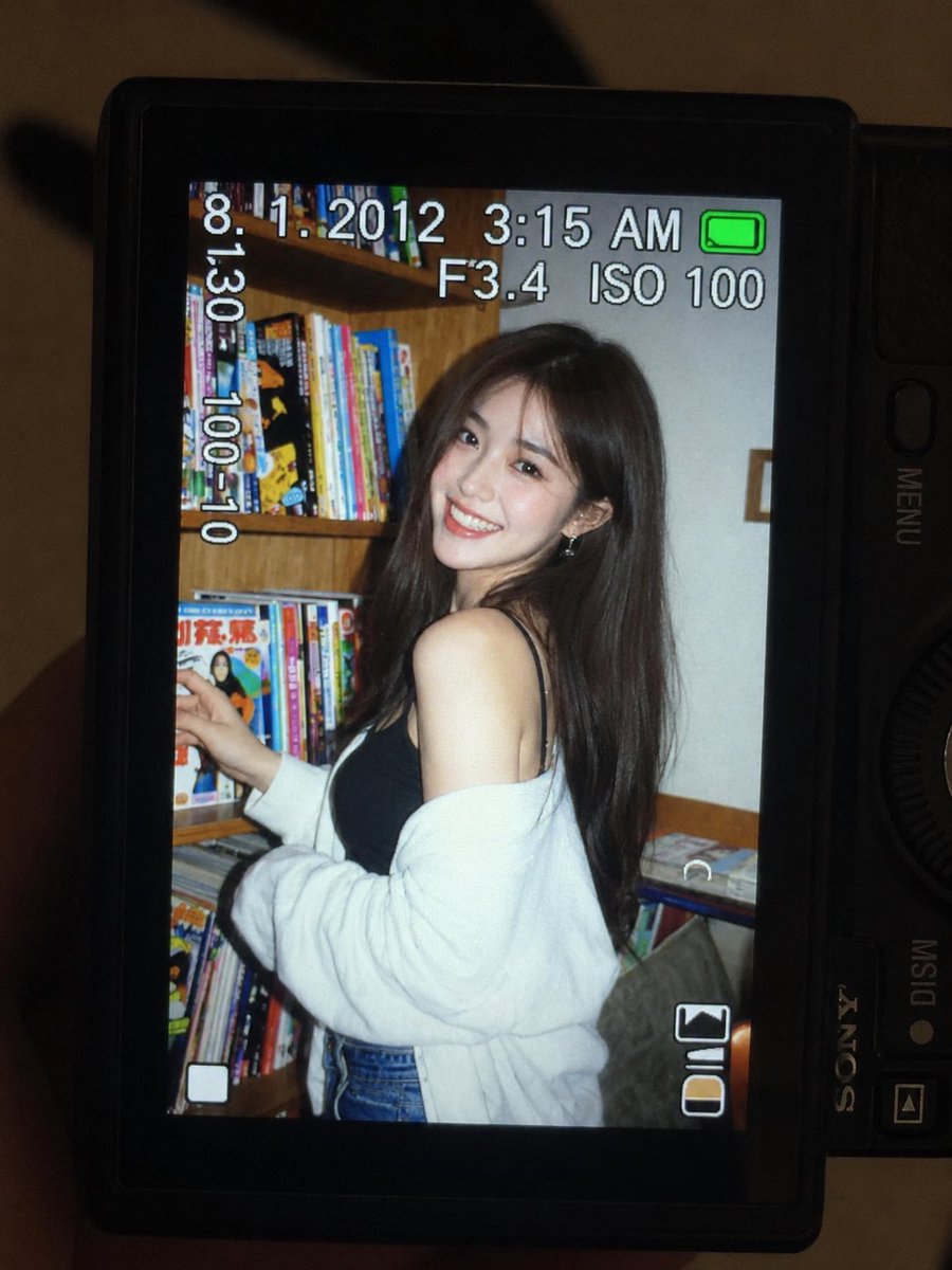 一张超精细的特写镜头：一台微型紧凑型数码相机的 LCD 屏幕在原本黑暗的室内房间中明亮发光。屏幕上是一张 2010 年代初期的随性傻瓜相机快照…, 图片 1