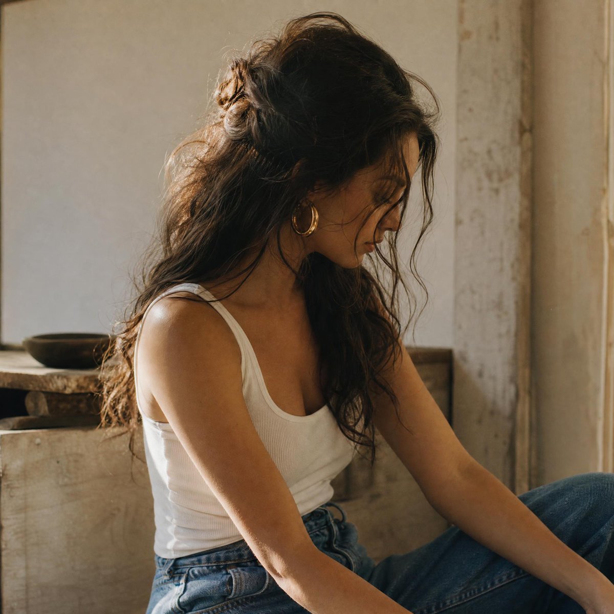 一张自然随性的中景人像照：一位女性拥有蓬松凌乱、波浪卷曲的深棕色长发，部分以半扎发样式向后别起，鬓角处有几缕碎发自然垂落，修饰着脸部轮廓。她若…, 图片 1