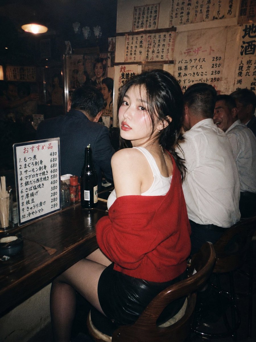 一位美丽的年轻东亚女性，留着深色波浪长卷发，妆容精致，夜晚坐在一家温馨昏暗的日本居酒屋的木质吧台前。她转过头，越过肩膀直视镜头，眼神妩媚诱人。…, 图片 2