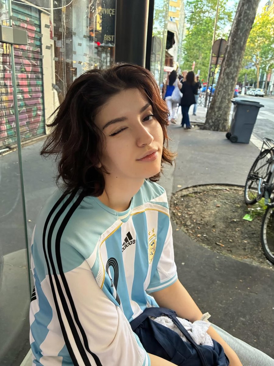 超写实的随性人像摄影:一位留着短波浪深色头发的年轻人,身着阿根廷国家足球队宽大球衣(19号),在黄金时段坐在城市公交车内和公交车站上。柔和温暖…, 图片 3