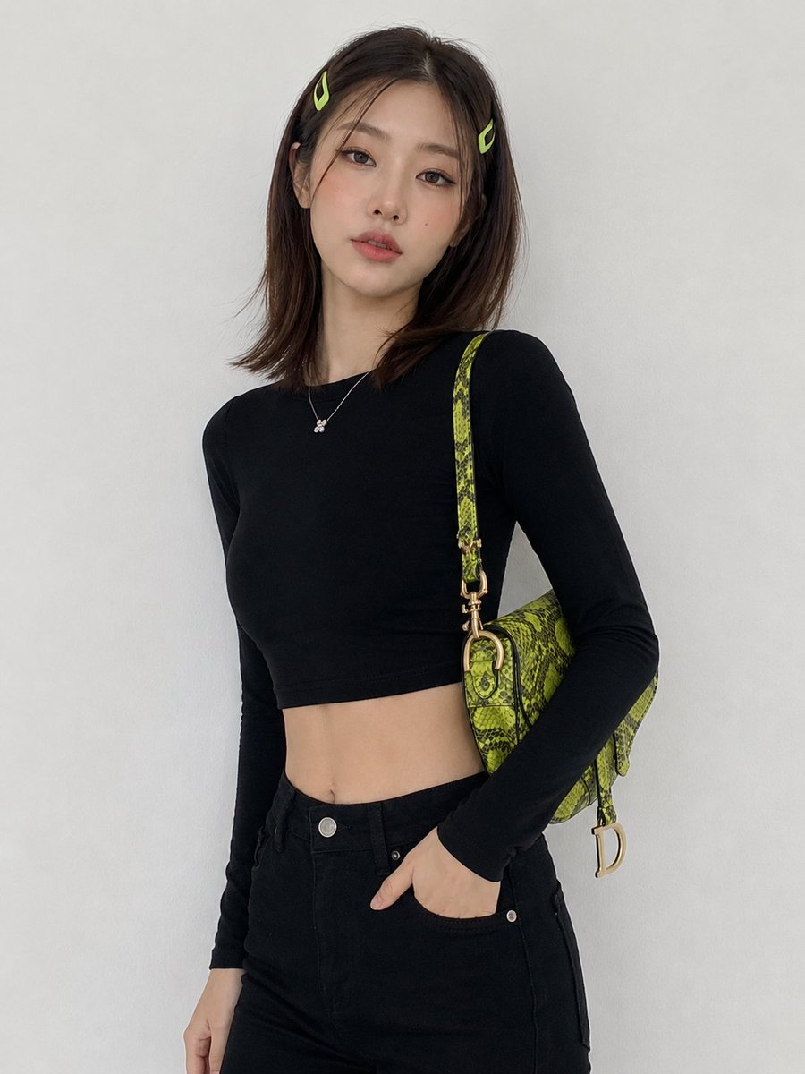 创建一幅图像:一位年轻韩国女性,中长棕色头发,两侧别着青柠绿色发夹,倚靠在一面纯白色墙壁前摆姿势,身穿黑色短款长袖上衣、黑色高腰长裤,肩上斜挎…, 图片 1