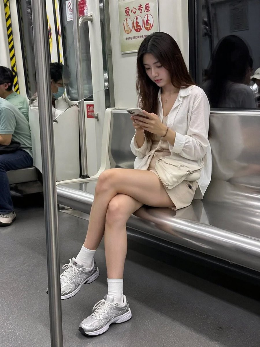 一位迷人的女士在乘坐地铁时低头看着她的智能手机,以随性的街头摄影风格拍摄。, 图片 1