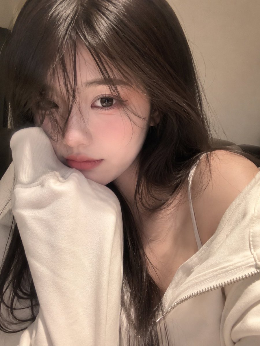 一张照片般逼真的特写自拍,一位可爱的年轻女性,脸部占据画面的大部分,头部微微倾斜,脸颊舒适地靠在一件宽松的奶油色连帽衫袖子里。柔顺的长发配有柔…, 图片 2