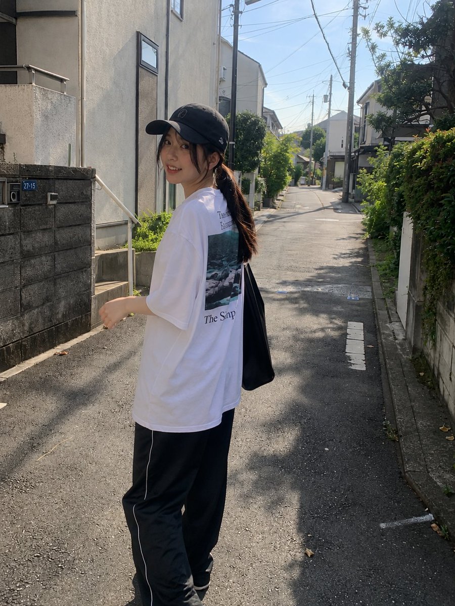 年轻漂亮的日本女孩,肤色白皙,妆容自然柔和,长长的深色头发在黑色棒球帽下扎成低马尾,身穿宽松的白色印花T恤和黑色宽松全长运动裤。在一个晴朗的下…, 图片 2
