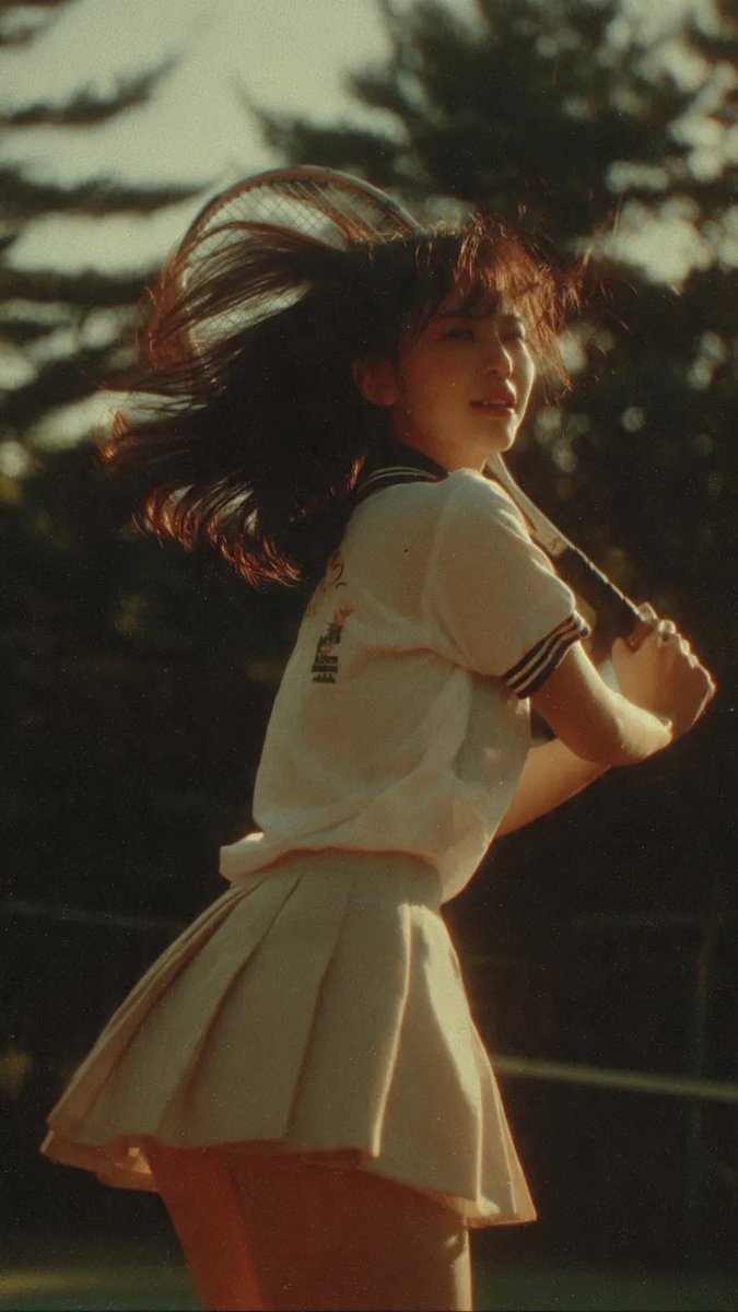电影感中景镜头：一名身穿网球服的日本少女，在网球比赛挥拍途中被自然抓拍，柔和阳光穿过树林，暖色调，90年代日本电影美学，轻微胶片颗粒感，风吹动…, 图片 1