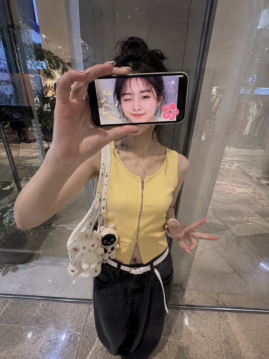 超现实创意iPhone人像照:一位时尚的日本女性站在现代购物中心的反光玻璃墙前,采用略微抬高的正面拍摄角度,呈现0.5x iPhone广角镜头…, 图片 1