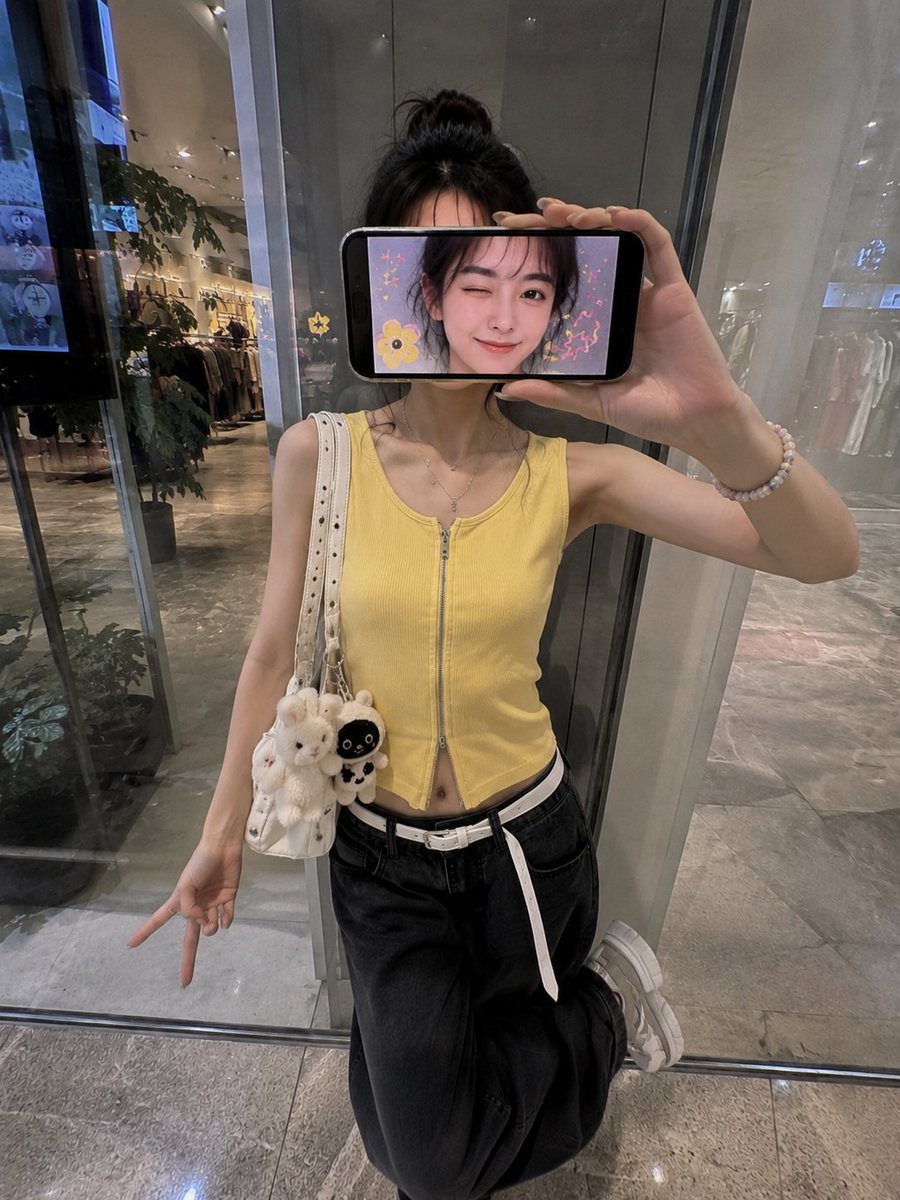 超现实创意iPhone人像照:一位时尚的日本女性站在现代购物中心的反光玻璃墙前,采用略微抬高的正面拍摄角度,呈现0.5x iPhone广角镜头…, 图片 2