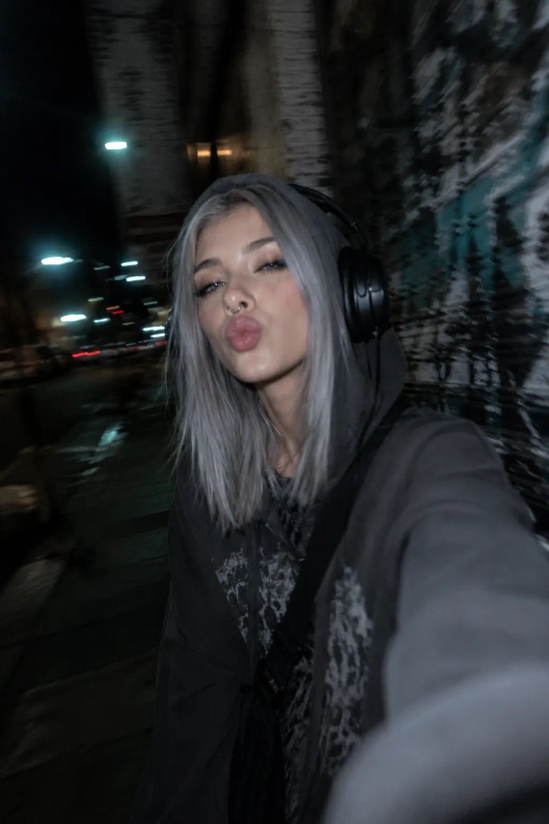 以所附照片为参考,创作一张夜间城市摄影人像,主体为一位年轻女性,整体呈现另类、垃圾摇滚(grunge)美学。她留着齐肩直发、中分,浅色眼睛搭配…, 图片 3