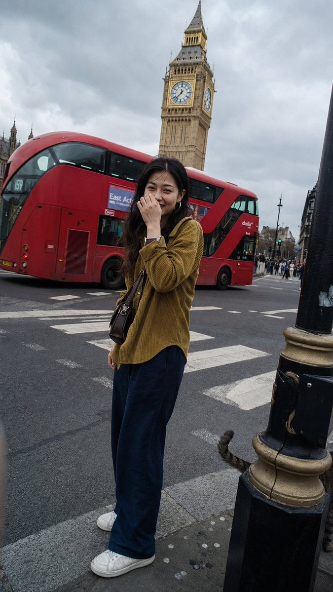 一张在伦敦街头随手拍摄的普通抓拍快照,看起来像是有人走在她前面,转身拍了一张照片。一位二十出头的年轻东亚女性站在人行横道前,她的容貌百分之百写…, 图片 1
