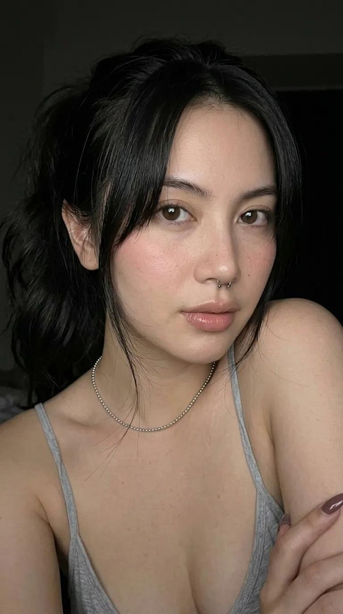 一张高端时尚工作室人像照,主体是一位年轻女性,肤色白皙,深棕色头发梳成光滑的高发髻。她呈紧凑的蹲姿,膝盖紧贴胸口。她平静、自信、神情平和地直视…, 图片 1