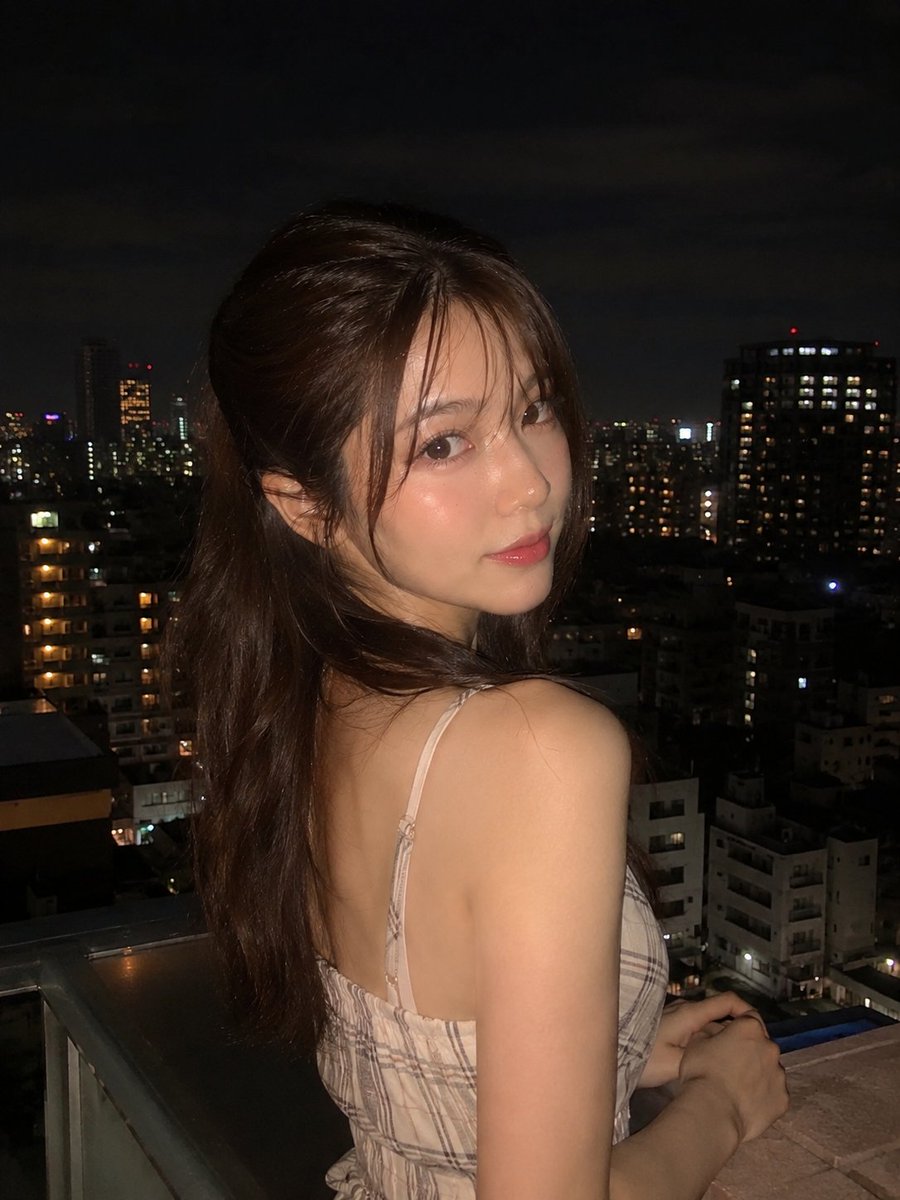 超写实夜景人像:一位美丽的年轻女子站在阳台上,俯瞰城市天际线,身穿优雅的无袖米色格纹连衣裙,淡雅腮红妆容,自然水润唇妆,慵懒的半扎发造型,几缕…, 图片 2
