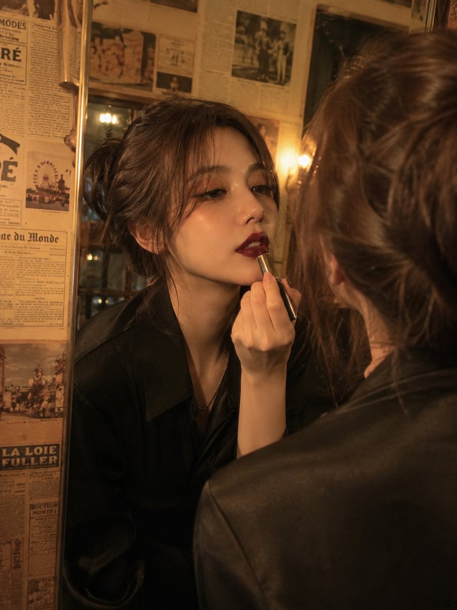 电影级复古美人肖像:一位优雅的年轻女性正在涂抹深酒红色口红,同时望向镜中,温暖的金色钨丝灯光在她脸上投下戏剧性的阴影,柔软的波浪棕色头发盘成略…, 图片 1