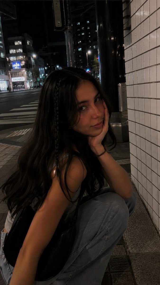 一段电影感十足的夜间街拍人像，写实抓拍风格，在日本城市安静的人行道上用 iPhone 拍摄。一位年轻女性沿着人行道行走，长而微卷的深棕色头发，…, 图片 2