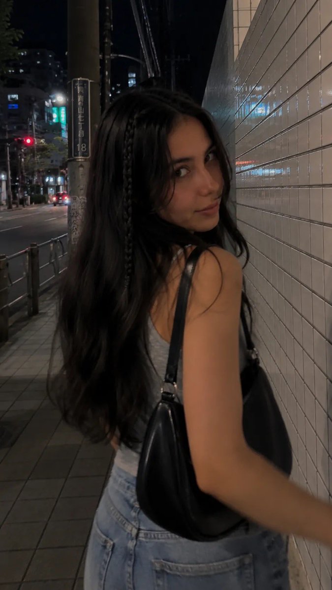 一段电影感十足的夜间街拍人像，写实抓拍风格，在日本城市安静的人行道上用 iPhone 拍摄。一位年轻女性沿着人行道行走，长而微卷的深棕色头发，…, 图片 3