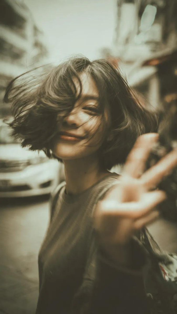 一张千禧年(Y2K)风格的街拍人像写真:一位开朗的年轻女性,留着凌乱的短波波头(bob),自然地开怀大笑,直接对着镜头比出胜利手势(V字手势/…, 图片 3