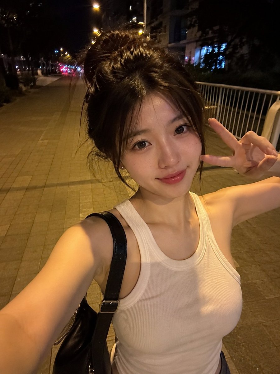 夜晚，一位美丽的东亚年轻女性在安静的城市人行道上户外行走的真实感智能手机自拍。她拥有瓷白肤色、闪亮的大眼睛呈深棕色、小巧笔挺的鼻梁、自然有光泽…, 图片 1