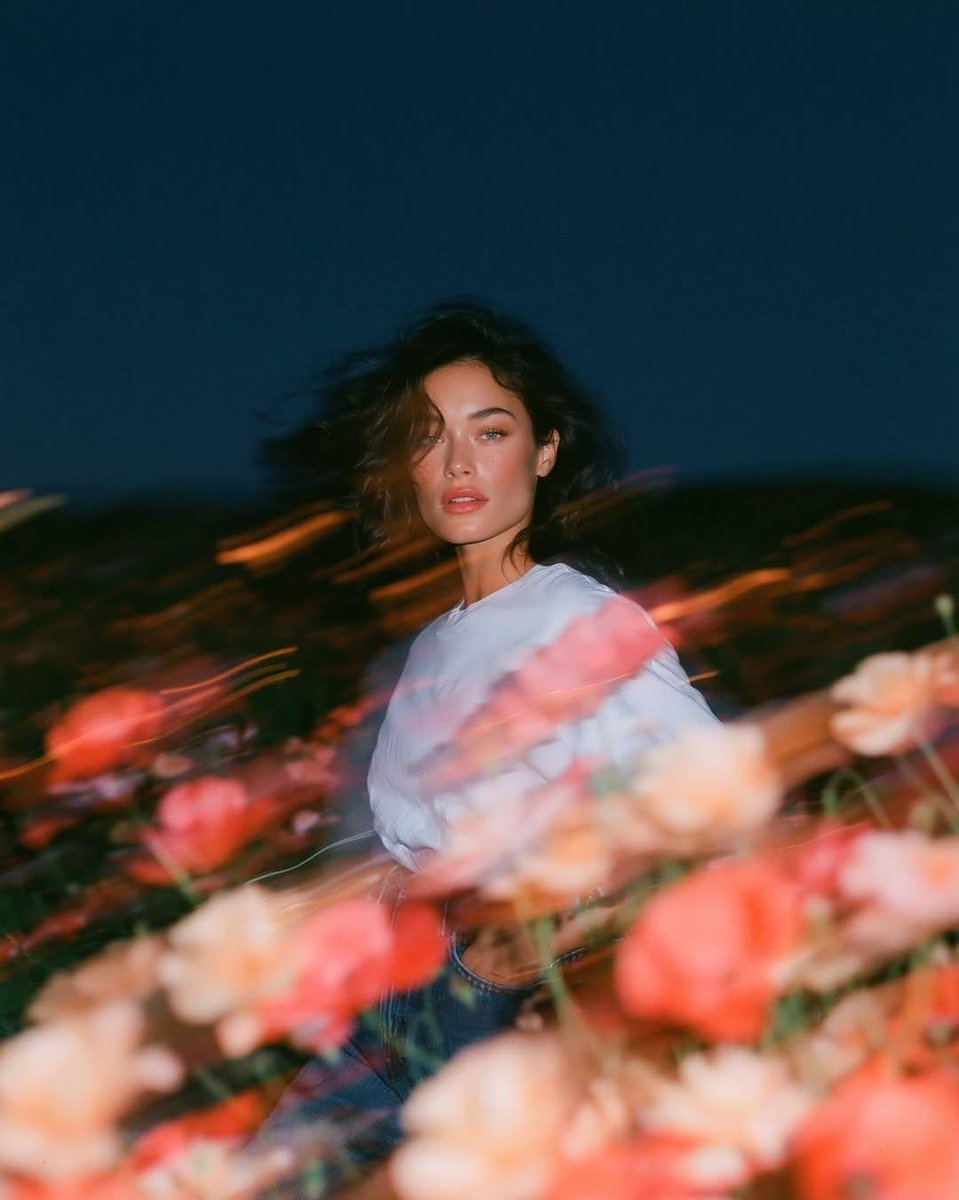 照片级真实的实验性时尚肖像,一位自然美丽的年轻女性正面站立于蓝调时刻风拂的野花田中,以齐眼水平高度从大腿向上取景。她身穿一件宽松的纯白棉质T恤…, 图片 2