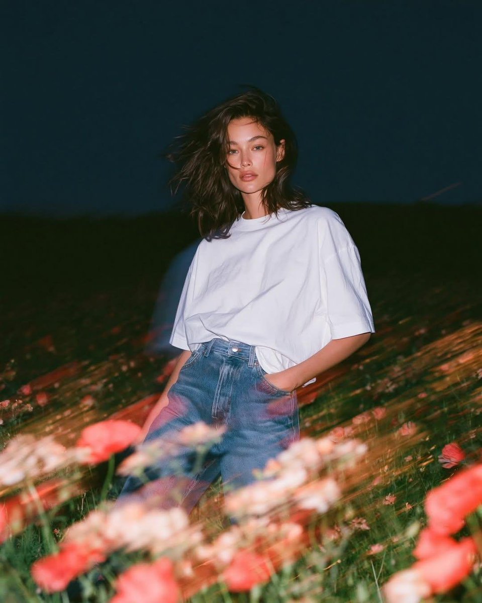 写实风格的实验性时尚人像:一位天生丽质的年轻女子正面站立于蓝色时刻狂风拂过的野花田中,镜头从大腿向上以平视取景。她身穿一件宽松的纯白棉质T恤,…, 图片 3