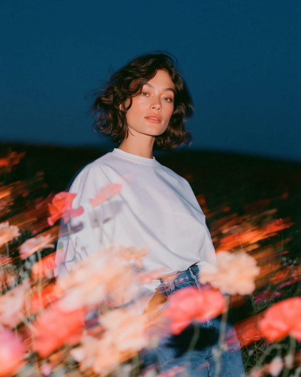 Create a cinematic fashion editorial portrait at blue hour in an open wildflowe…