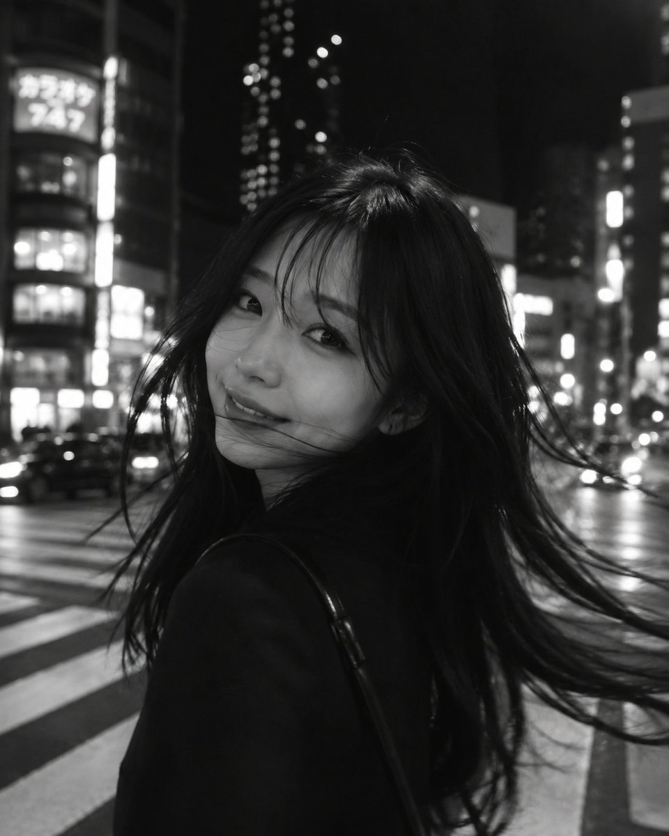 一张黑白电影感的城市夜景摄影作品,采用长曝光与刻意营造的运动模糊。画面前景中是一位年轻女子,略微偏离中心,正在转身的瞬间,她的长发以柔和、如幽…, 图片 1
