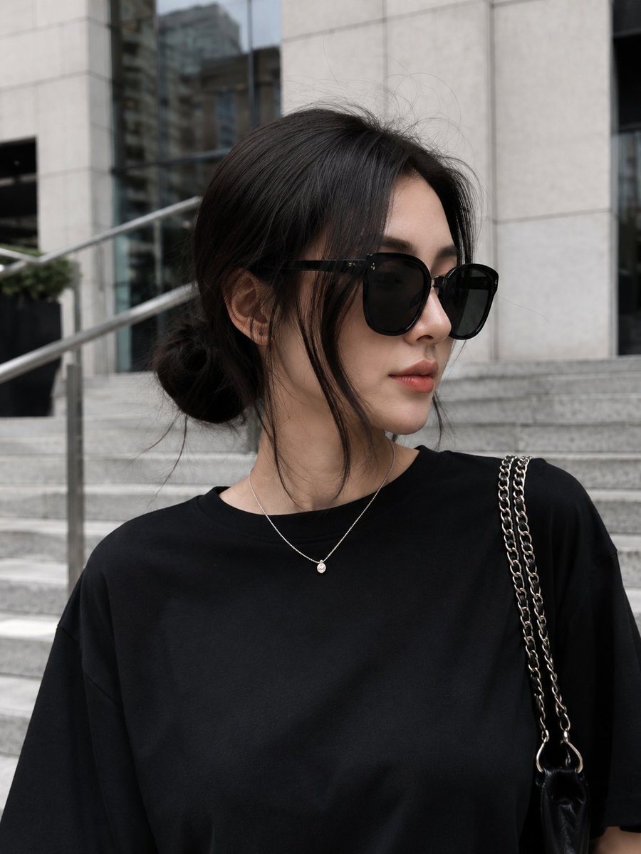 极简奢华街头风格时尚人像:一位时尚年轻女性自信地走下一座当代建筑外的宽阔现代花岗岩石阶。她身穿超大号黑色T恤,搭配宽松的黑色阔腿裤,脚踩清爽的…, 图片 1