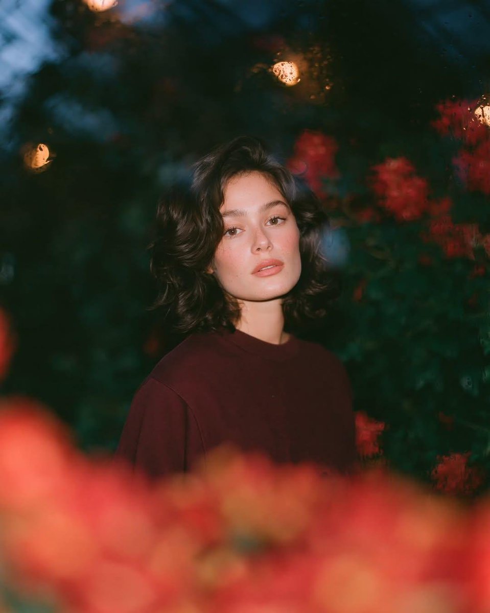 梦幻的电影感夜景人像:一位美丽的年轻女性,留着短款波浪深色头发,皮肤散发着自然光泽,身穿一件宽松的酒红色圆领卫衣,夜晚站在一座郁郁葱葱的花园中…, 图片 3