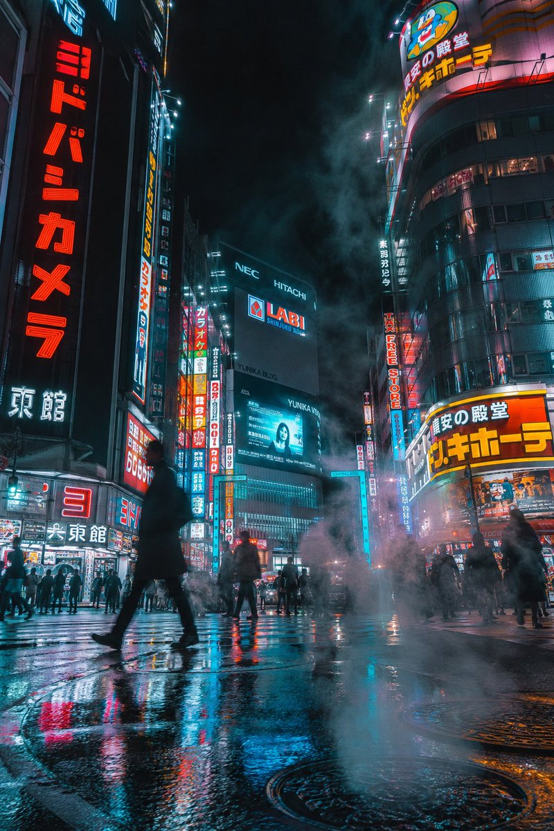 夜晚的未来赛博朋克城市街道,竖向构图。霓虹招牌(包含清晰的日文文字)在高耸的摩天大楼上发光。湿润的人行道倒映着鲜艳的灯光与全息广告。浓重的蒸汽…, 图片 2