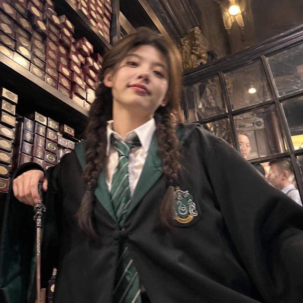 Transform the person into a young woman wearing a Slytherin Hogwarts-style scho…