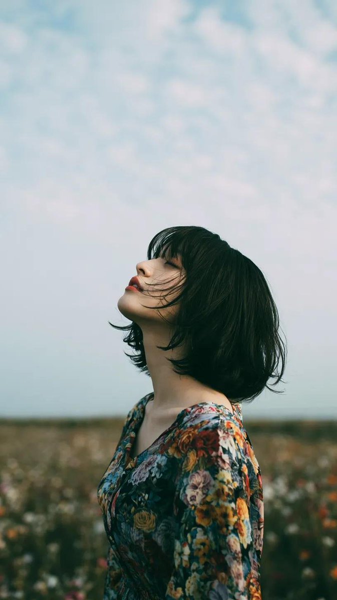 电影极简风格人像：一位美丽的年轻东亚女性独自站立在一片开阔的野花草地上，头顶是无尽的蓝天，她微微仰头，双眼或闭或半睁，仿佛在拥抱风。黑色长发自…, 图片 4