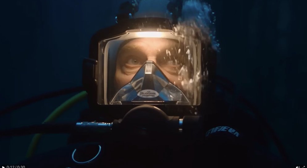A lone deep-sea diver descends slowly into the ruins of a submerged cathedral r…
