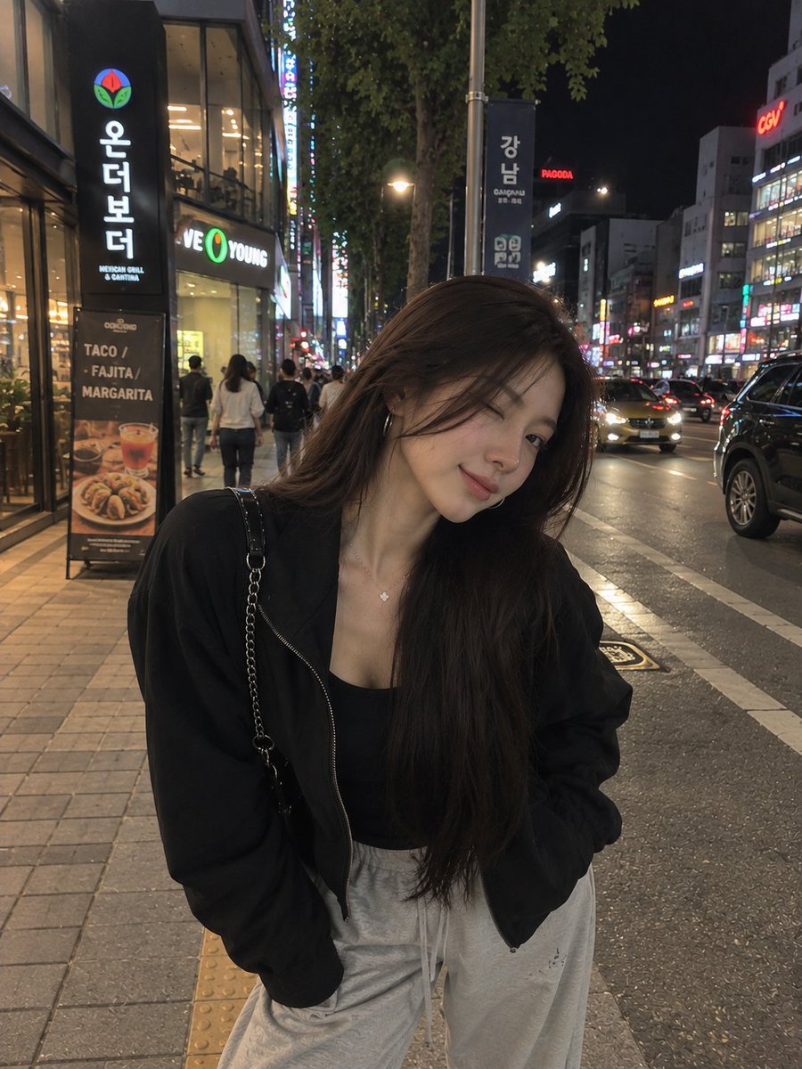 一张照片级写实风格的夜间街头人像照,一位年轻女子在繁华的韩国城市街区中随意地自拍。她留着长而顺直的黑发,妆容柔和自然,佩戴着低调的环形耳环和一…, 图片 1