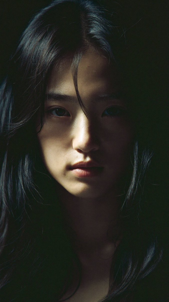 特写电影感人像:一位年轻的东亚女性,长长的略带凌乱的黑发披在肩上,几缕散发拂过脸庞。她直视镜头,表情平静、专注而略带忧郁。左侧柔和而戏剧性的侧…, 图片 3