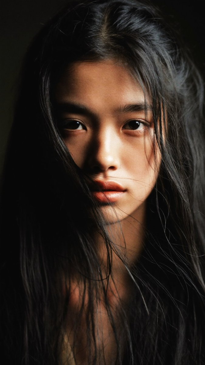 特写电影感人像:一位年轻的东亚女性,长长的略带凌乱的黑发披在肩上,几缕散发拂过脸庞。她直视镜头,表情平静、专注而略带忧郁。左侧柔和而戏剧性的侧…, 图片 4