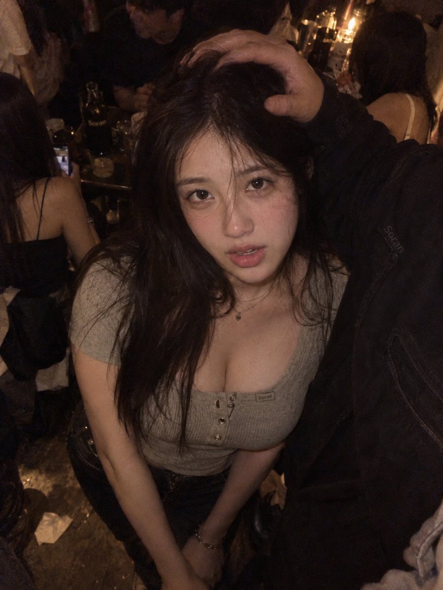 3:4 竖幅,真人写实夜间聚会快照风人像,成年东亚女性位于画面中央偏左,近距离高机位俯拍,摄影机明显高于人物眼睛。人物身体基本正向镜头,头部略…, 图片 1